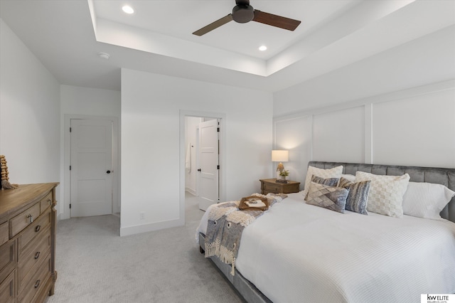 bedroom with light carpet, recessed lighting, ceiling fan, a tray ceiling, and connected bathroom