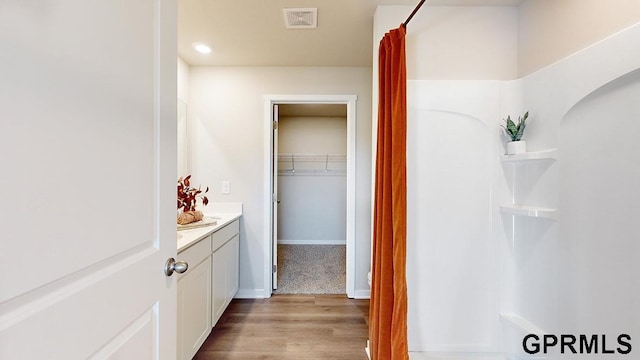 bathroom with visible vents, a shower, wood finished floors, vanity, and recessed lighting