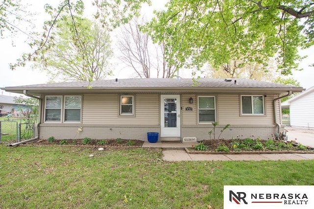 ranch-style home with brick siding, fence, and a front lawn