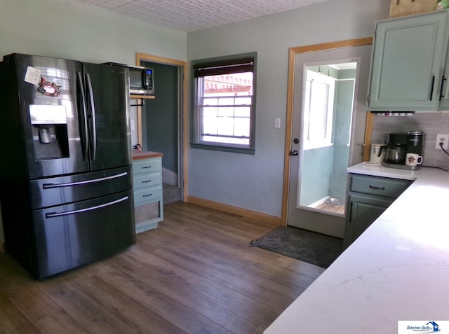 kitchen with light countertops, baseboards, black fridge, and wood finished floors