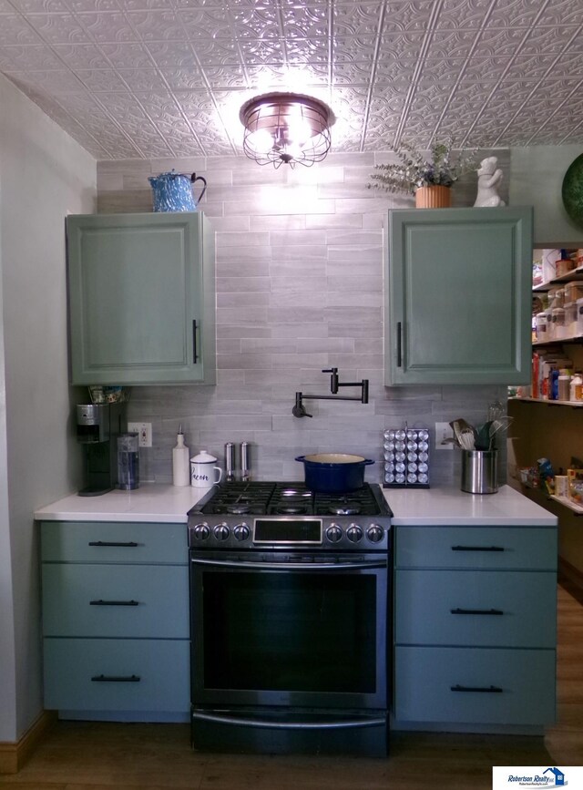 kitchen with gray cabinets, stainless steel range with gas stovetop, light countertops, an ornate ceiling, and dark wood-type flooring