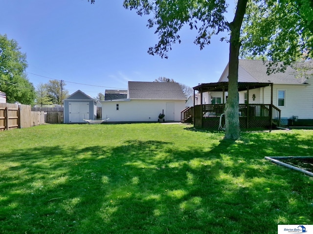 view of yard with fence, a storage unit, a wooden deck, and an outdoor structure