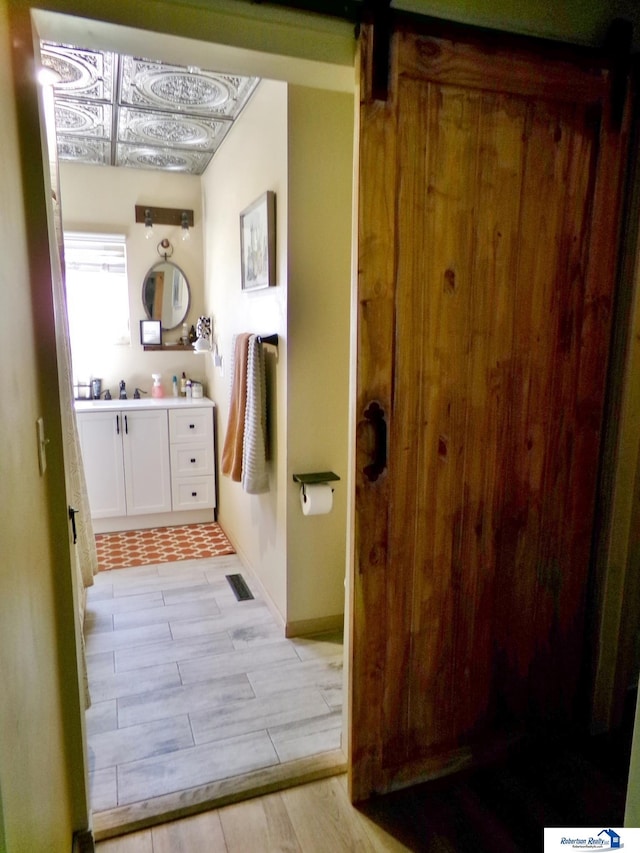 bathroom with vanity, baseboards, wood finished floors, and visible vents