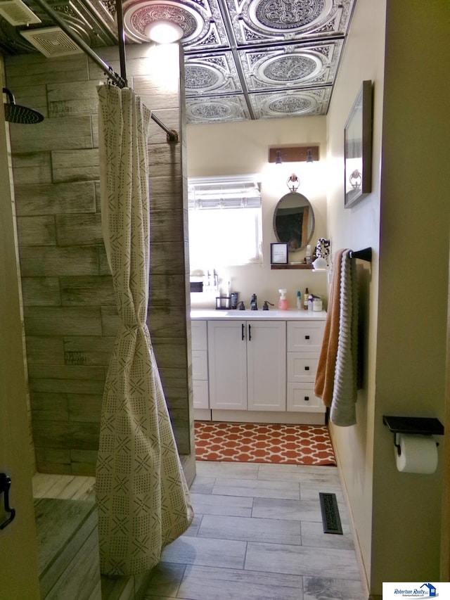 bathroom with vanity, a tile shower, and visible vents