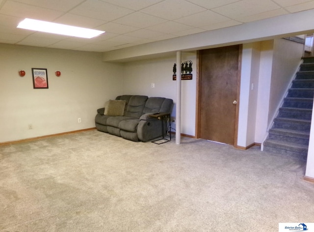 sitting room with stairs, a drop ceiling, and carpet
