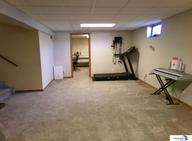 exercise room with baseboards, carpet, and a paneled ceiling