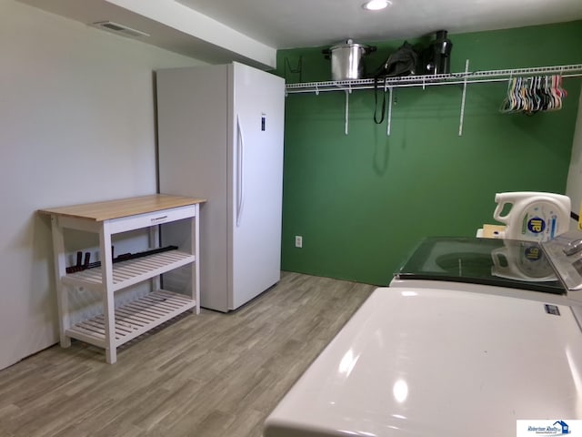 laundry room featuring visible vents, laundry area, wood finished floors, and washer and clothes dryer