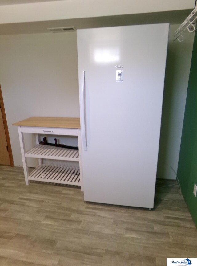 details featuring visible vents, freestanding refrigerator, and wood finished floors