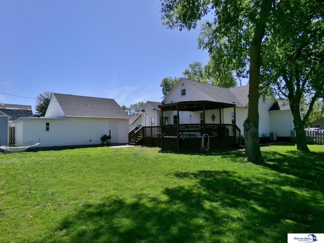 rear view of property with a wooden deck and a yard