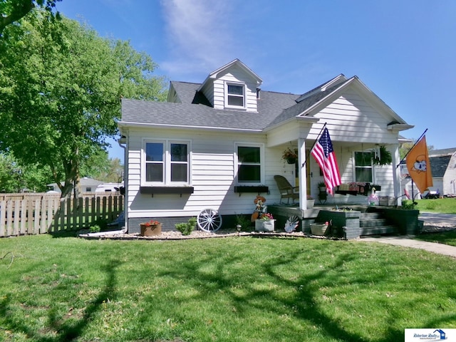 view of front facade featuring a shingled roof, a front lawn, fence, and covered porch