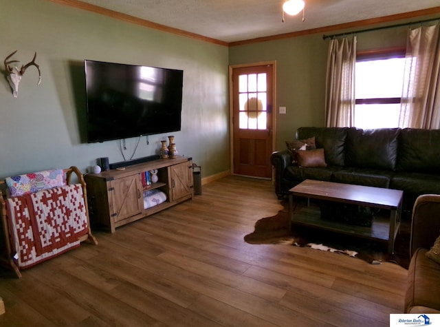 living room featuring crown molding, baseboards, and wood finished floors