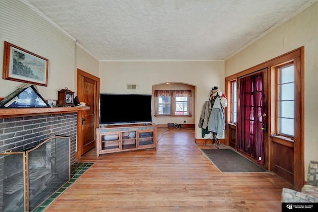 entrance foyer with ornamental molding, a textured ceiling, a brick fireplace, and wood finished floors