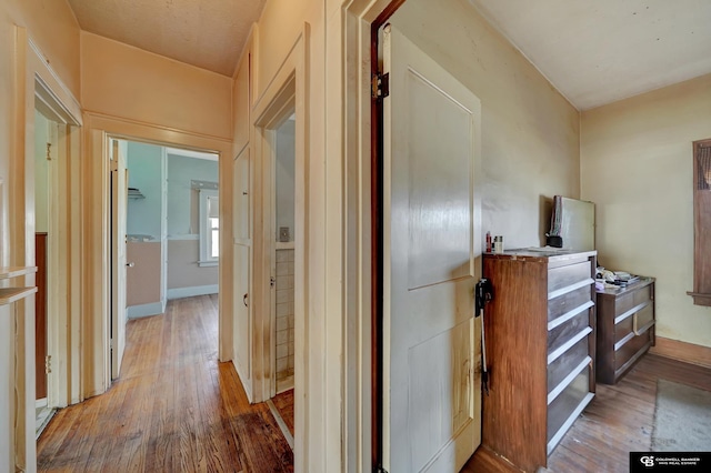 corridor featuring baseboards and wood finished floors