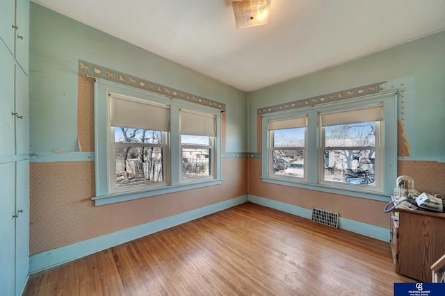 unfurnished room with wood-type flooring, baseboards, and visible vents