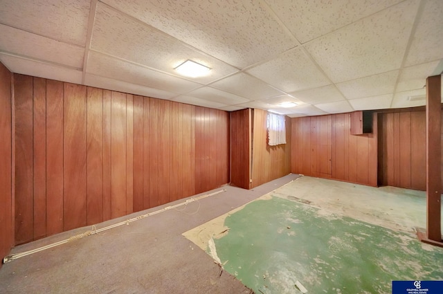 finished below grade area featuring wooden walls and a paneled ceiling