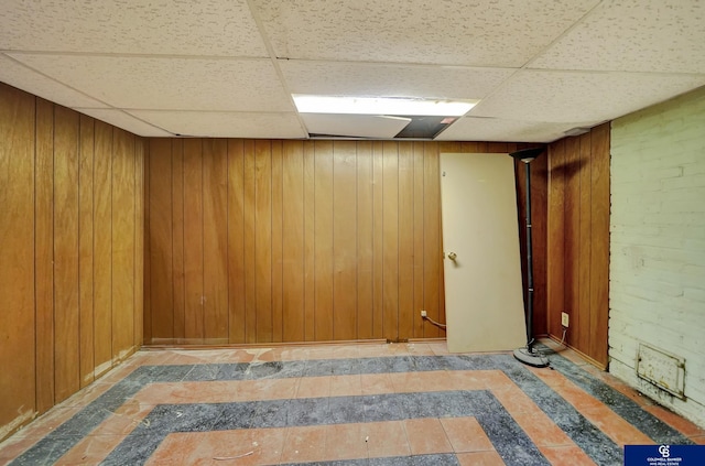 finished basement featuring wood walls and a paneled ceiling