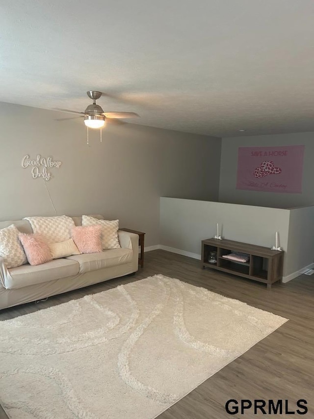 living room with baseboards, a ceiling fan, and wood finished floors