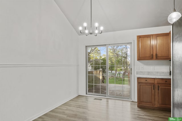 unfurnished dining area with visible vents, an inviting chandelier, light wood-style flooring, and vaulted ceiling