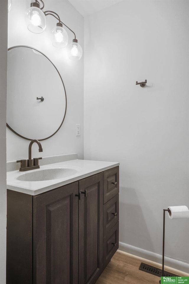 bathroom featuring baseboards, wood finished floors, and vanity