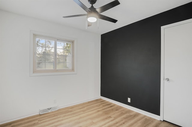 spare room with a ceiling fan, baseboards, visible vents, and light wood-style flooring