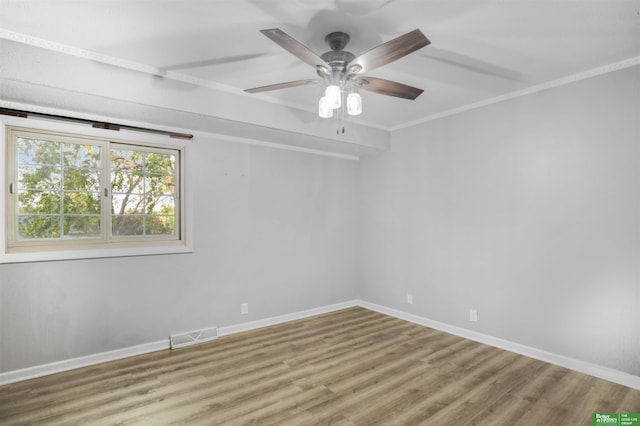 spare room with baseboards, a ceiling fan, wood finished floors, and visible vents