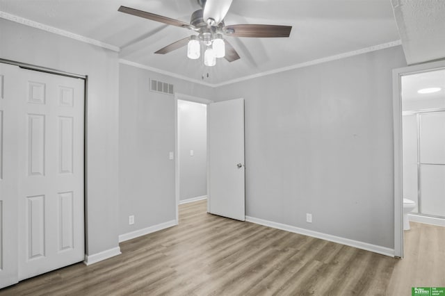 unfurnished bedroom with connected bathroom, baseboards, wood finished floors, visible vents, and ornamental molding