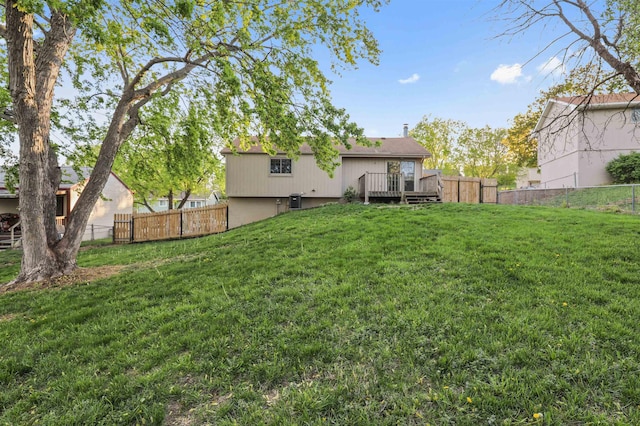 rear view of property featuring a lawn, a deck, and a fenced backyard