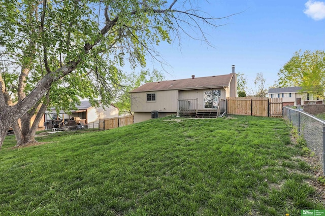 rear view of house with a fenced backyard, a yard, and a deck