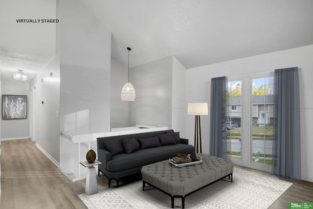 living area featuring baseboards, wood finished floors, and lofted ceiling