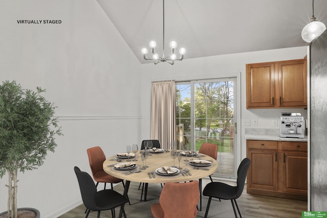 dining area with high vaulted ceiling, wood finished floors, and a notable chandelier