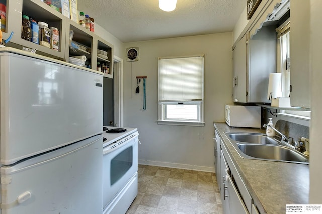 kitchen featuring visible vents, white appliances, baseboards, a textured ceiling, and a sink