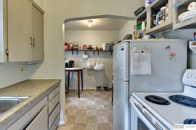 kitchen with a sink, open shelves, electric range, and stone finish flooring