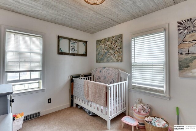 bedroom featuring visible vents, carpet flooring, a nursery area, and multiple windows