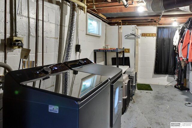 clothes washing area with concrete block wall, separate washer and dryer, and laundry area