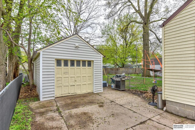 detached garage featuring fence and concrete driveway