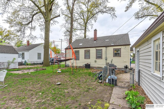 rear view of house with fence, a gate, a chimney, and cooling unit