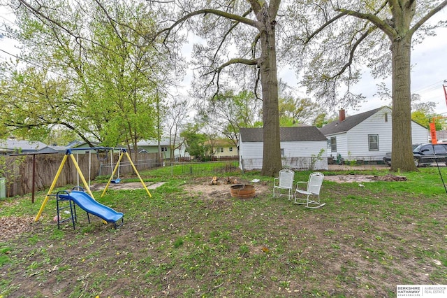 view of yard featuring a fenced backyard, a playground, and a fire pit