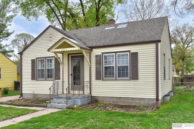 view of front of home with roof with shingles, fence, a chimney, and a front lawn