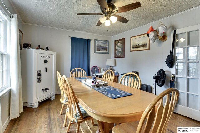 dining space with a ceiling fan, a textured ceiling, a healthy amount of sunlight, and wood finished floors