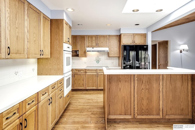 kitchen with black refrigerator with ice dispenser, decorative backsplash, range hood, and light wood-style floors