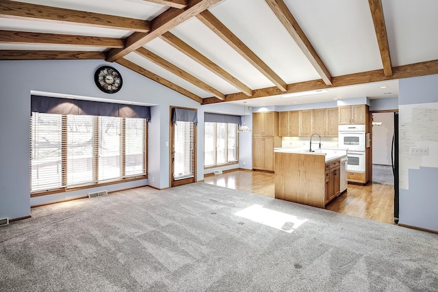 kitchen with a kitchen island with sink, visible vents, light colored carpet, light countertops, and open floor plan