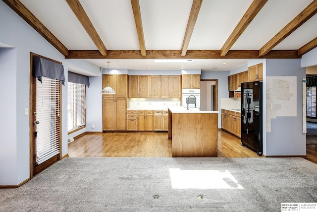 kitchen with black refrigerator with ice dispenser, a kitchen island with sink, oven, vaulted ceiling with beams, and light countertops