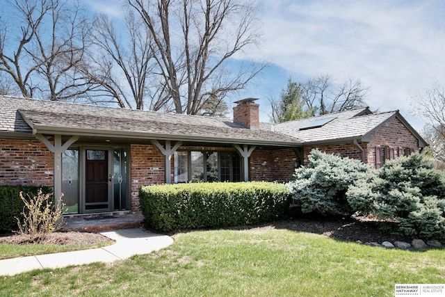 ranch-style house featuring a chimney, a front lawn, and brick siding