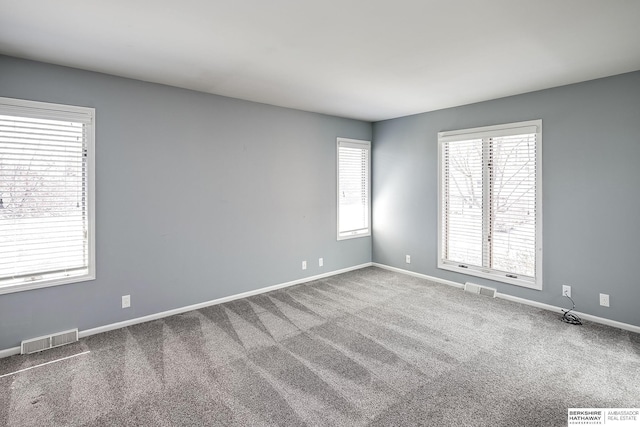 carpeted empty room with visible vents and baseboards