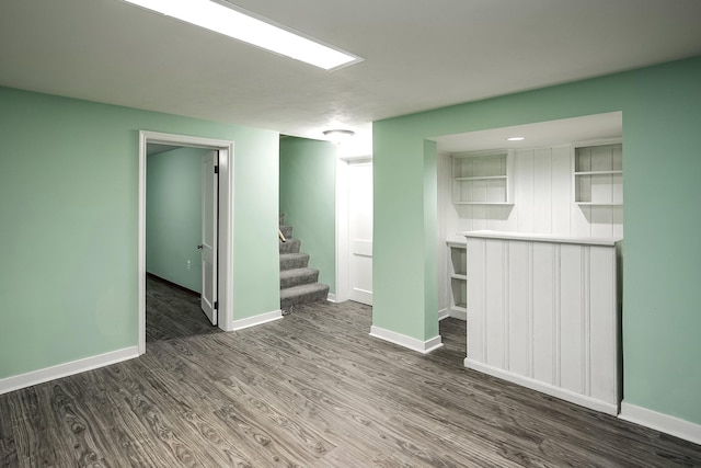 empty room featuring baseboards, wood finished floors, and stairway