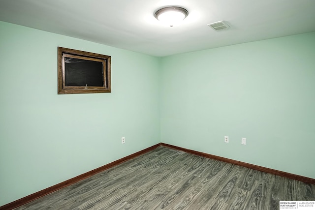 spare room with baseboards, visible vents, and wood finished floors