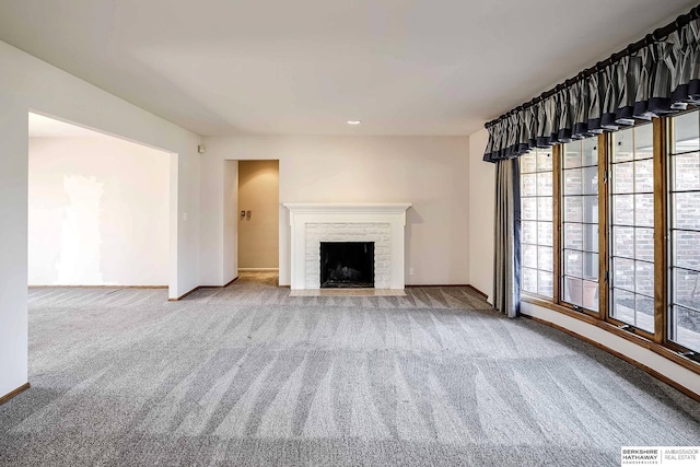 unfurnished living room with carpet flooring, baseboards, a fireplace with flush hearth, and visible vents