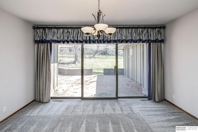 unfurnished dining area featuring baseboards, an inviting chandelier, and carpet