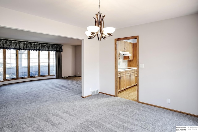 empty room with light colored carpet, baseboards, visible vents, and an inviting chandelier