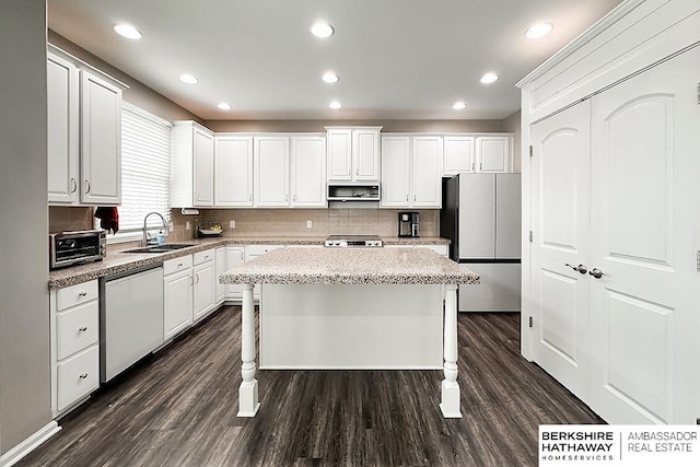 kitchen with dark wood-style flooring, a kitchen island, white cabinetry, a sink, and stainless steel appliances